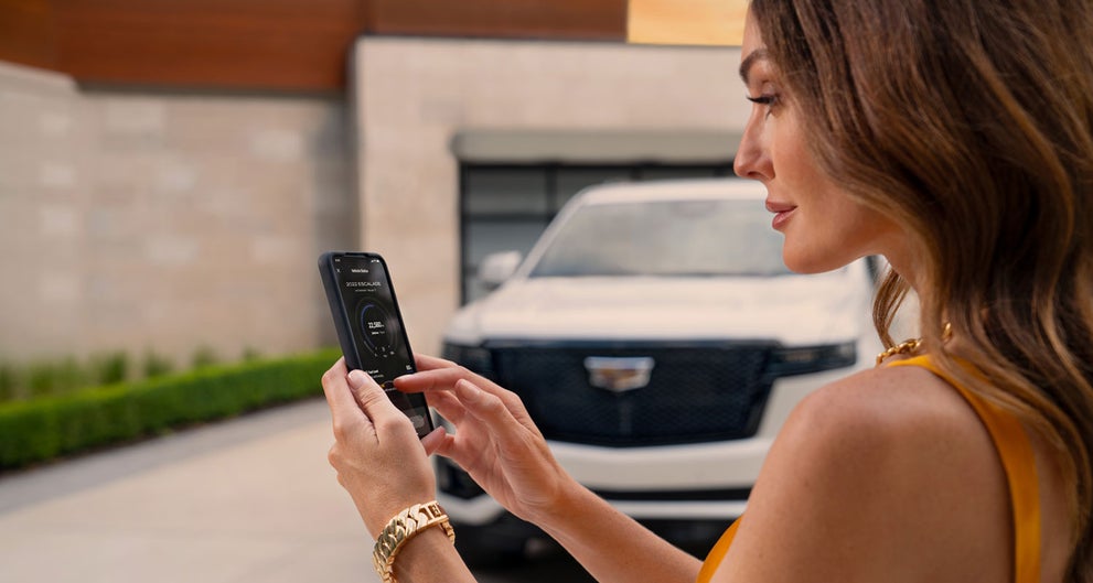 lady checking her mobile with a Cadillac vehicle background | Bergstrom Cadillac of Madison in Madison WI